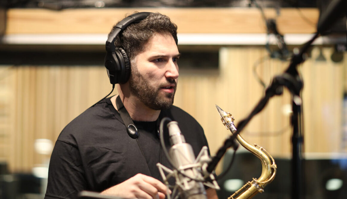 A man with headphones on holding a saxophone.