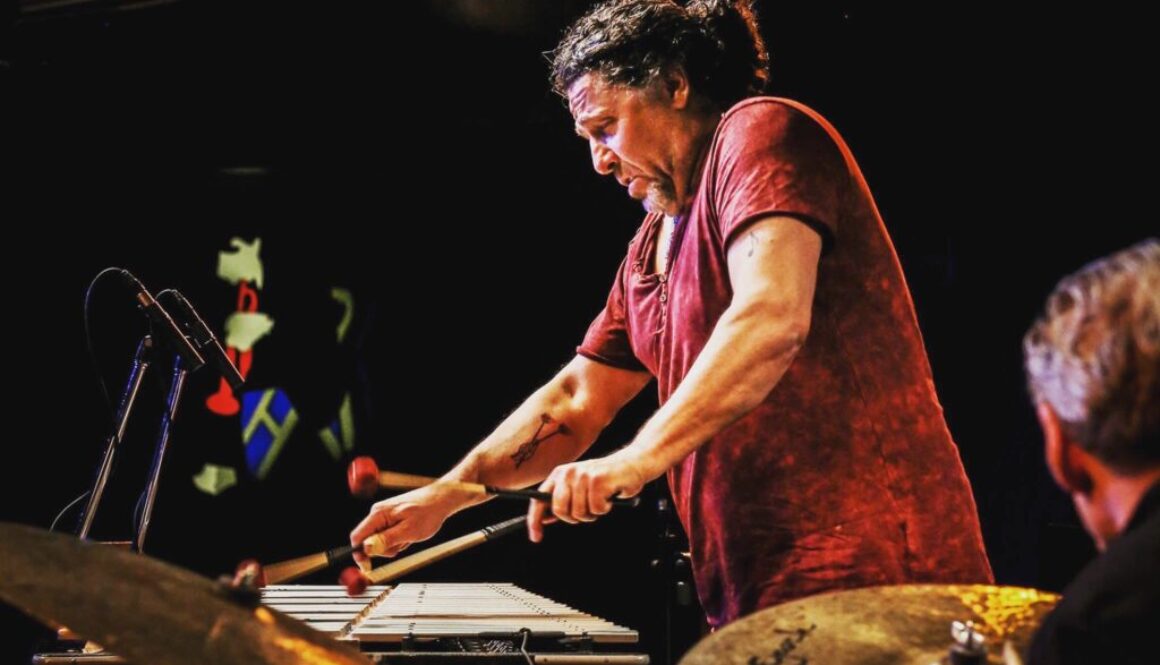 A person playing drums on stage with other people