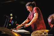 A person playing drums on stage with other people